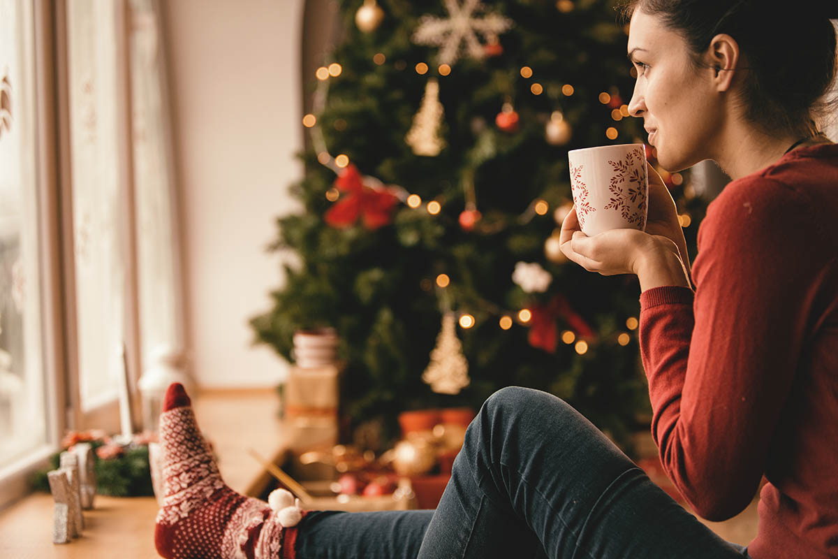 Young woman drinking tea by the Christmas tree