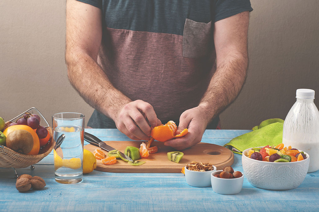 Man preparing a fruit salad in the kitchen at home